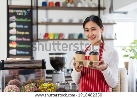 Portrait of woman owner standing at her coffee shop gate holding a cup of coffee
