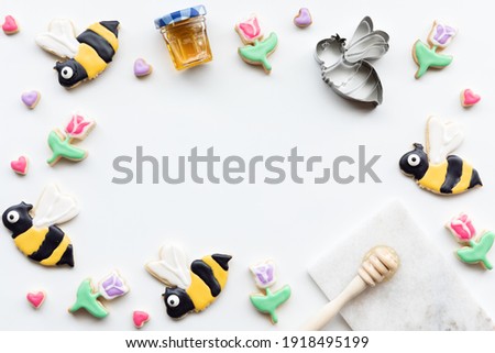 Top down view of a border of sugar cookies in shapes of bees, tulips and hearts. A spring and summer concept.