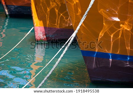 The stern of two fishing ships anchored in the harbor