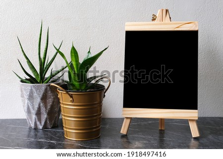 Blank black wooden board, chalkboard, standing over white cement wall with copy space, template, Blackboard mock up, template background