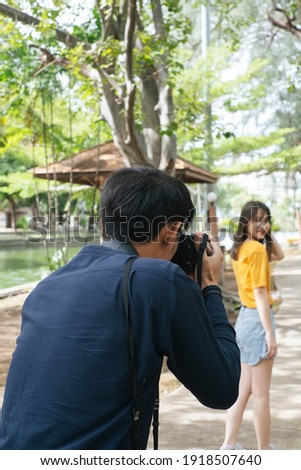 Photographer take a photo of female teenage model while she standing on the walk path in the park.