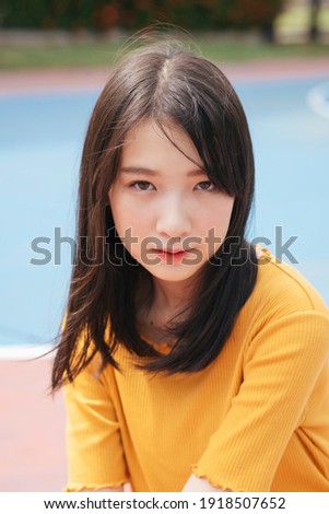Brunette girl standing, jumping and sitting in basketball court in sunny day.