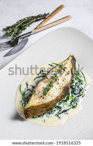 Baked Halibut fish steak with spinach. White background. Top view