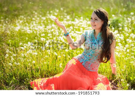 beautiful girl resting on the glade with dandelions