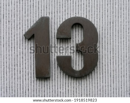 13, close up house number thirteen on concrete wall 