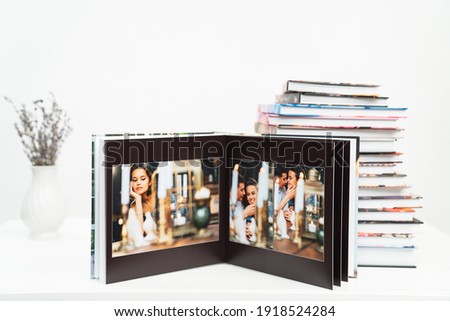 a stack of books. open photobook from photo shoots of a a beautiful happy couple in a retro country house. grainy paper texture. photo design in the album. Memory. Designer. black background 