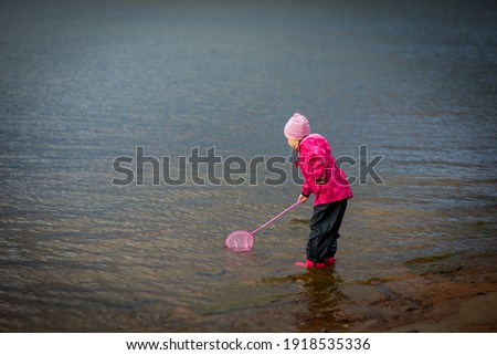 a girl in a pink jacket plays on the riverbank, selective focus