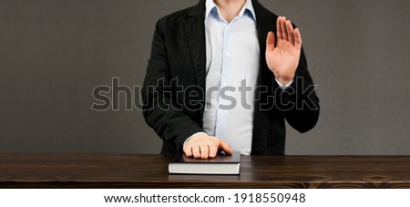 Oath. Witness. Hand on a closed Bible book. Taking an oath and promise with a raised hand. The man in the shirt. Royalty-Free Stock Photo #1918550948