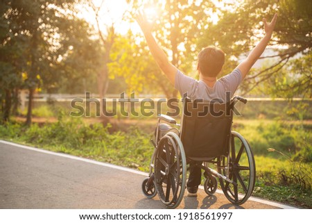 Happy Paralyzed,disabled or handicapped man in hope sitting relax on a wheelchair in nature park.Disabled handicapped man has a hope use smart phone for working,calling and searching for social media Royalty-Free Stock Photo #1918561997