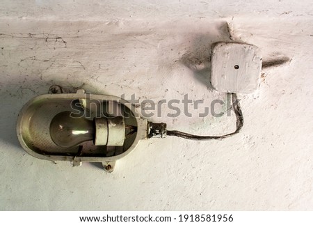 Industrial old ceiling lamp (storage or factory lamp) with vintage off bulb on dirty white wall in a warehouse, basement or attic Royalty-Free Stock Photo #1918581956