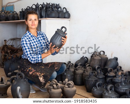 Woman chooses pots clay pots in store warehouse. High quality photo