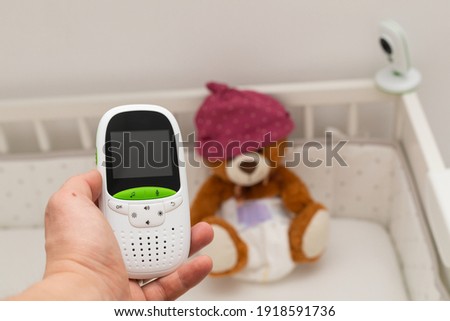 Picture of a baby monitor, camera and a teddy bear in  child room