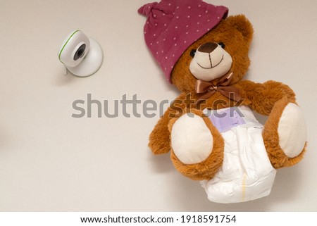 Picture of a baby monitor, camera and a teddy bear in  child room