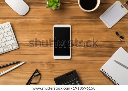 Overhead above close up view photo of office supplies with plant flower identity card binder clip glasses and telephone with empty blank space isolated brown backdrop