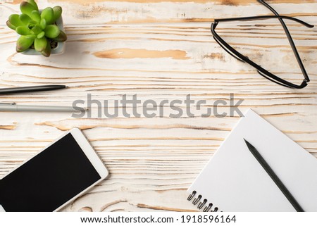 Overhead above close up view photo picture of eyeglasses cellphone notebook succulent stationery isolated white wooden backdrop with empty blank space