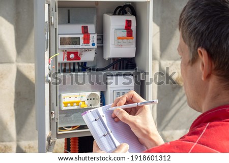 Man taking readings of an electric meter Royalty-Free Stock Photo #1918601312