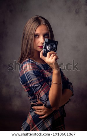 Girl photographer holding an old camera in her hands, studio photography on a gray background