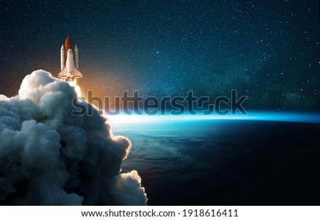 Space rocket lift off into cosmos with smoke and blast on a background of the blue planet earth. Spacecraft flies in space with a starry sky near the planet. Successful start of the mission Royalty-Free Stock Photo #1918616411
