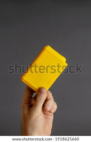 Hand holds 8 bit video game cartridge on gray background. Yellow Cartridge for TV games. Selective focus. Close-up.