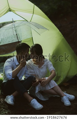 Young Asian couple kissing in the rain
