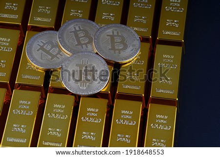 Gold bars next to each other on a black background and bitcoin digital cryptocurrency coin. Bank image and photo background. Shiny precious metal for investment or as a reserve. Place for text.