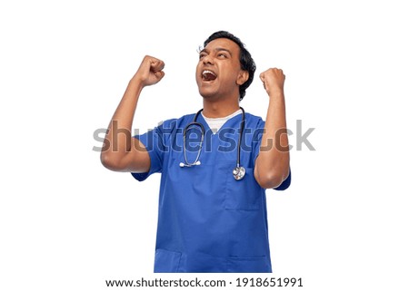 healthcare, profession and medicine concept - happy smiling indian doctor or male nurse in blue uniform celebrating success over white background