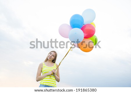 Portrait of Young adult Beautiful birthday caucasian girl with colorful balloons on blue cloudy sky background Copy space for inscription Cute woman looking at camera