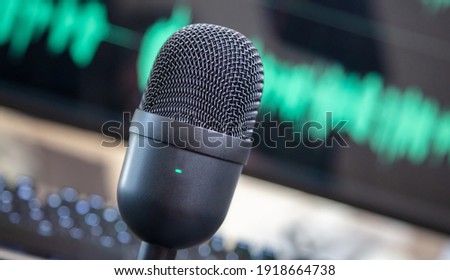 Tlted condenser mic, blur console and turquoise waveform background. Sound recording concept. Microphone for live audio, music, speech, concert, performance, closeup view