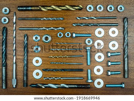 Knolling style photo - various bolts, nuts, drills and washers for mechanical repair on a background of brown wood texture