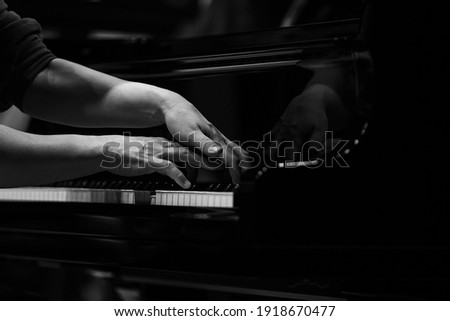 Hands of a woman playing the piano close up in black and white