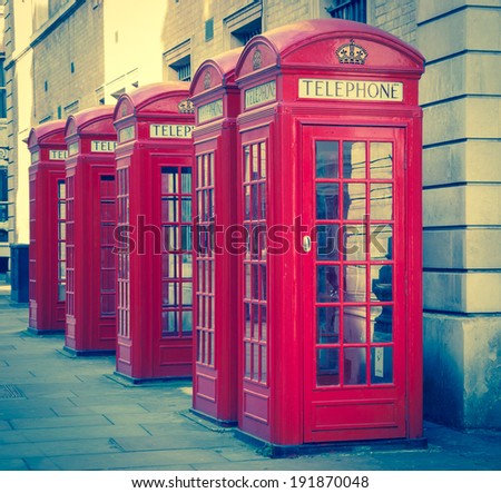 Five traditional old style red phone boxes in London, UK. Aged photo.