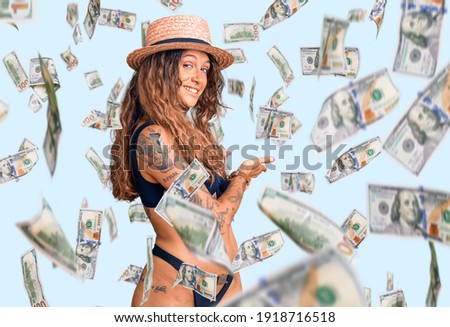 Young hispanic woman with tattoo wearing bikini and summer hat inviting to enter smiling natural with open hand