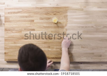 Man treats wooden surface of table with a protective varnish. Wood care concept