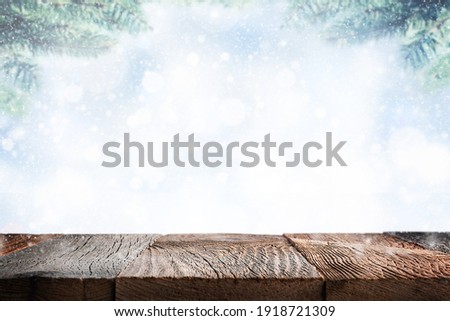 Empty wooden table surface over blue winter background with snow. Template for product display