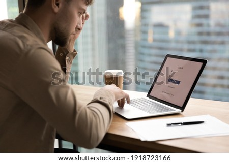Thoughtful young man worker, student sit by laptop, prepare to input personal data entering account. Pensive millennial guy creating strong login password to electronic bank. Close up Royalty-Free Stock Photo #1918723166