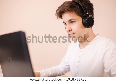 Teenage boy playing game on laptop in his room. Steamer use wireless headphones. Happy gamer play all day