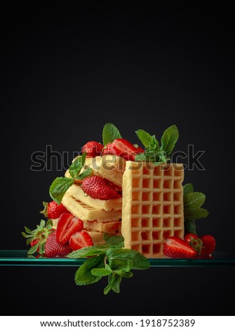 Waffles with strawberries and mint on a dark background, copy space.