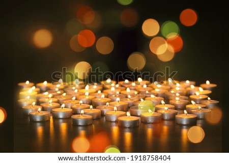 Bright candles on a reflective base with glittering bokeh