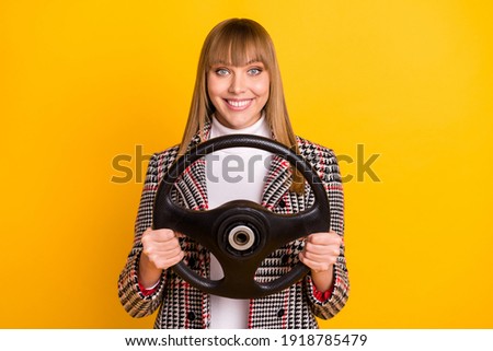 Photo of satisfied young girl arms holding wheel beaming smile look camera isolated on yellow color background