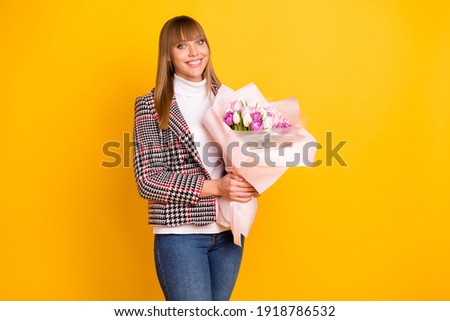Portrait of gorgeous satisfied person arms hold flowers look camera beaming smile isolated on yellow color background