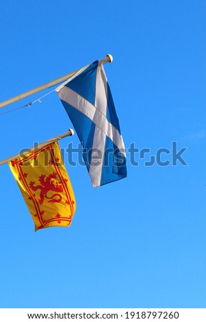 Scottish Saltire and Lion Rampant Flags on Flagpoles on Blue Sky Background in Edinburgh Scotland