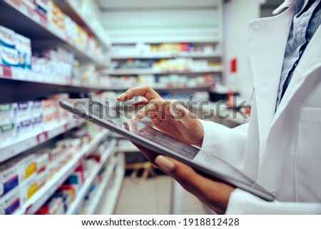 Closeup of hands of young female pharmacist checking inventory in medical store using digital tablet Royalty-Free Stock Photo #1918812428