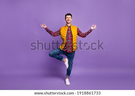 Full length photo of cute sporty young man wear yellow sleeveless jacket practicing yoga isolated violet color background Royalty-Free Stock Photo #1918861733