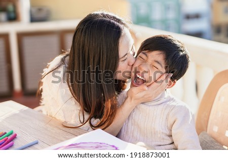 Asian mother kissing his little son outdoor on patio - Mother and child love Royalty-Free Stock Photo #1918873001