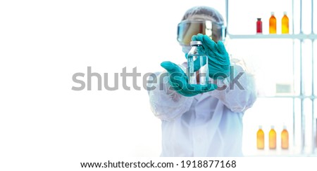 The person in chemical protection demonstrating a flask of colorless liquid. Royalty-Free Stock Photo #1918877168