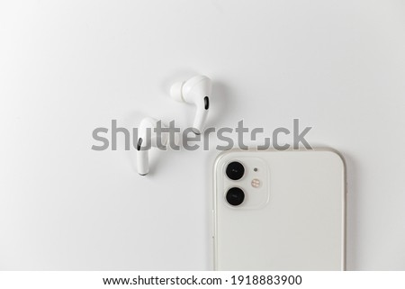 white wireless headphones on a white background. With a white smartphone Royalty-Free Stock Photo #1918883900