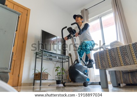 Stock photo of happy woman using stationary bike at home.
