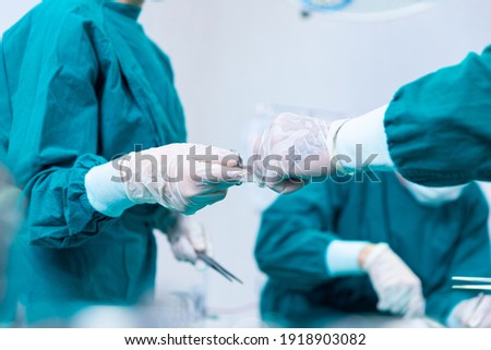 The surgeon was handed a pair of scissors by another doctor. Close-up of surgeons hands holding surgical scissors and passing surgical equipment. Royalty-Free Stock Photo #1918903082