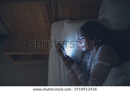 Asian woman playing game on smartphone in the bed at night,Thailand people,Addict social media Royalty-Free Stock Photo #1918912436