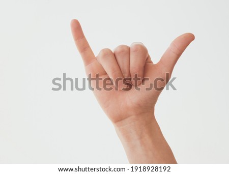 Woman hand in shaka or calling gesture on a white isolated background Royalty-Free Stock Photo #1918928192